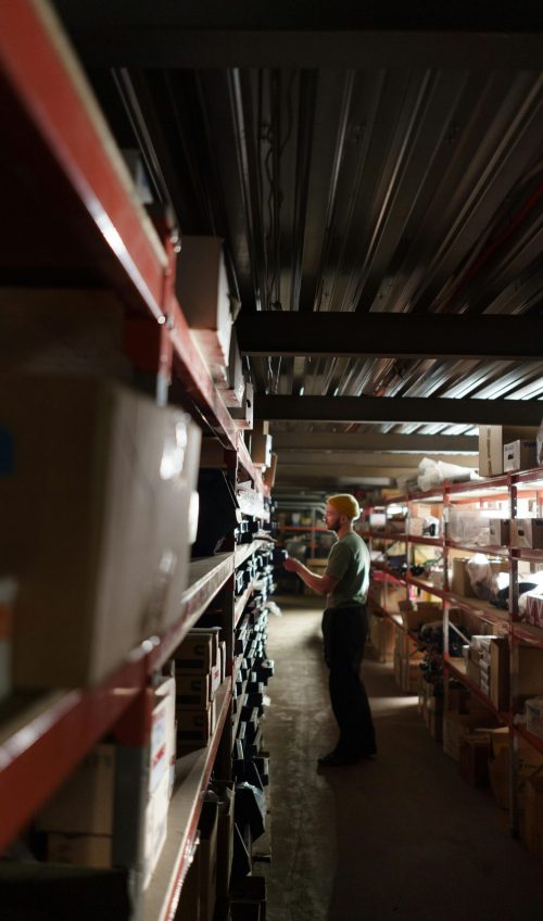 A worker organizing shelves in a dimly lit warehouse environment.